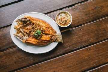 Delicious Asian - Asia eating Thai food. Fried fish on plate with vegetables. in a plate and wooden table background.