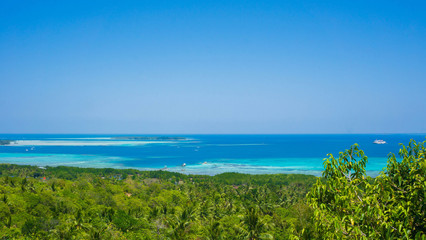 Fototapeta na wymiar a forest and deep blue sea view from bukit love