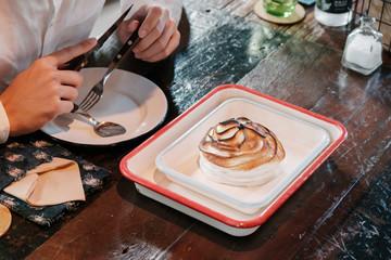 Fototapeta premium Asian man Eat Fine dining dessert, burnt ice cream in white vintage plate over wooden table