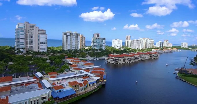 Zooming shot including a boat in the bay, condominiums and hotels in the background with the coastline of the Gulf of Mexico behind that.