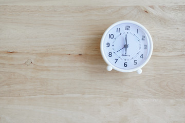 white circle clock on light brown wood background , morning wake up concept