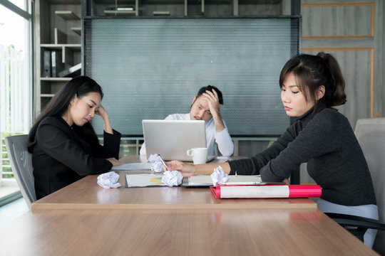 Group Of Unhappy Asian Business People In Casual Suit Sitting In Business Meeting Room And Looking Strain.