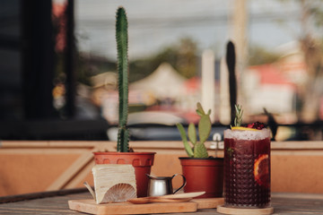 Iced tea with lemon and raspberry in tall glasses and strawberry crepe cake on rustic table decorated with cactus tree © Pantira