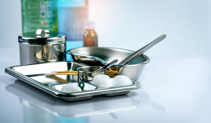 Wound care dressing set on stainless steel plate. White cotton ball, cotton stick, forceps, alcohol, iodine cup, instruments container  with cover or stainless steel cotton jar set. Medical tool.