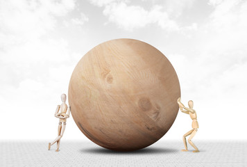 Man pushes a huge wooden ball and another sabotages it. Abstract image with a wooden puppet