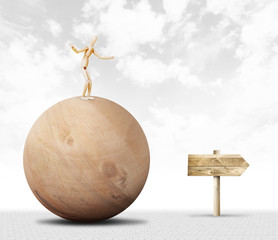 Man stands on the top of a huge wooden ball and moving towards the pointer. Abstract image with a...