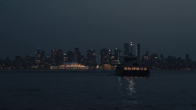 Sea bus arriving on North Shore at night with Vancouver skyline in background