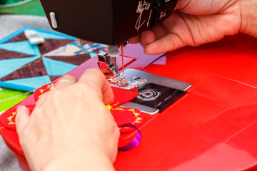 Seamstress sews material on a sewing machine. Close-up