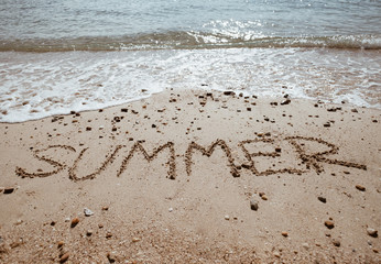 Summer wording on sand sea beach for coming season concept.