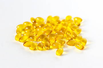 Shiny, yellow multivitamin softgels on light background