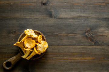 Chanterelle mushroom. Fresh raw chanterelles in fry pan on dark wooden background top view copy space