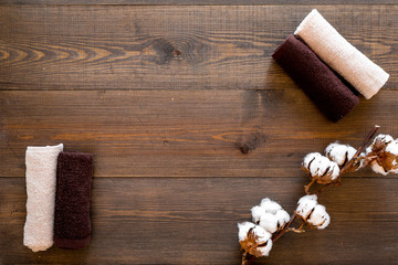 Fototapeta premium Cotton towels high quality. Set of towels twisted coil near dry cotton flowers on dark wooden background top view space for text