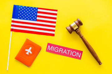 Immigration to United States of America concept. Textimmigration near passport cover and USA flag, judge hammer on yellow background top view