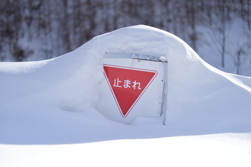雪に埋もれた「止まれ」の標識