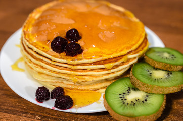 Delicious pancakes with honey, kiwi and berries.