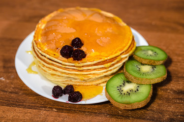 Delicious pancakes with honey, kiwi and berries.