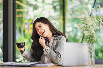 Obraz premium Portrait of an attractive young woman holding her phone while working in coffee shop.