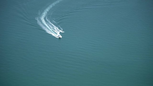 View from a hostel on the 66th floor of a building in Dubai of two people water skiing behind a boat in the ocean.