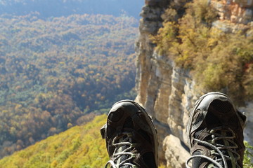 Image of torn trekking boots against the backdrop of mountains.