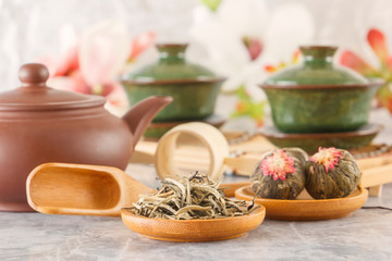 green tea and attributes for tea ceremony - a ceramic teapot, cups, a strainer, chopsticks and tweezers are placed on an old wooden table