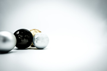 Black, silver and golden Christmas baubles on white background.