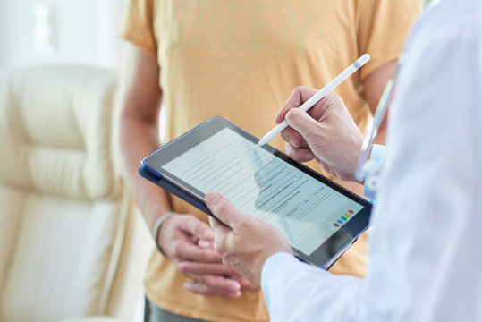 Doctor filling medical card on digital tablet when talking to patient