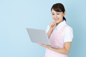 portrait of young asian nurse wearing apron on blue background