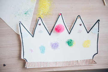 Pompons, paper crown, spangles. Project of children's creativity, handicrafts, crafts for kids. 