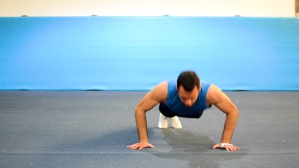 a guy doing a special kind of push up
in a top/side/front view still shot
inside a gymnastics gym