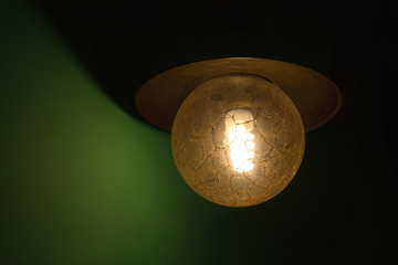 Illuminated lamp on the green wall, soft dark shadow