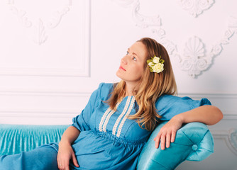 Blond attractive pregnant women on the sofa.Studio shooting.