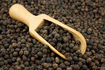 Black pepper scattered with a wooden scoop
