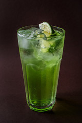 Glass of mojito with ice and slice of lime on elegant dark brown background