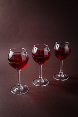 3 small glasses of red liquor on elegant dark brown background
