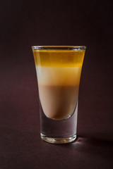BMW alcoholic shot glass with irish cream, whiskey, coconut liquor on elegant dark brown background