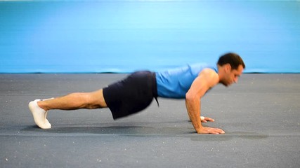 a guy doing a special kind of push up
in a top/side/front view still shot
inside a gymnastics gym