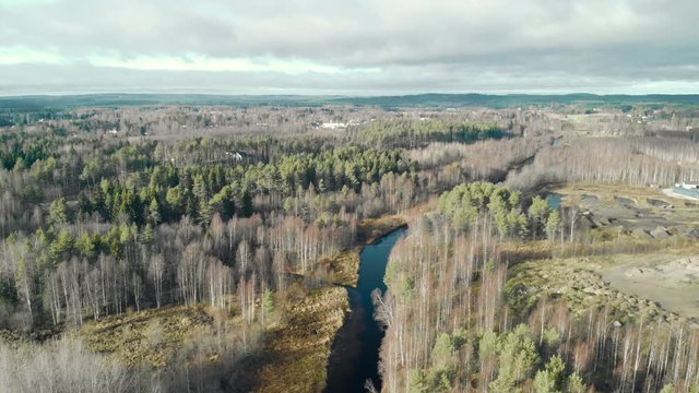 Aerial, drone shot, flying towards a river, in a leafless, autumn forest, on a cold, half cloudy, fall day, in Juuka, North Karelia, Finland