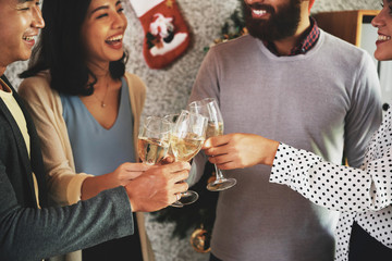 Group of joyful young people laughing and toasting with champagne glasses at Christmas party