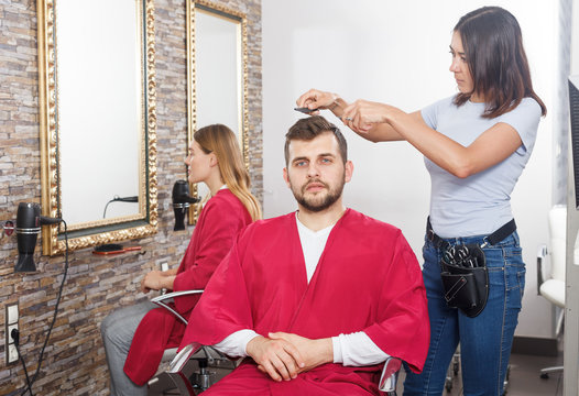 Woman professional hairdresser cut male's hair in hairdressing salon