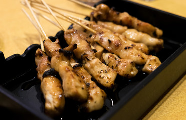 Yakitori Japanese style skewered chicken grilled on charcoal fire served with sauce.