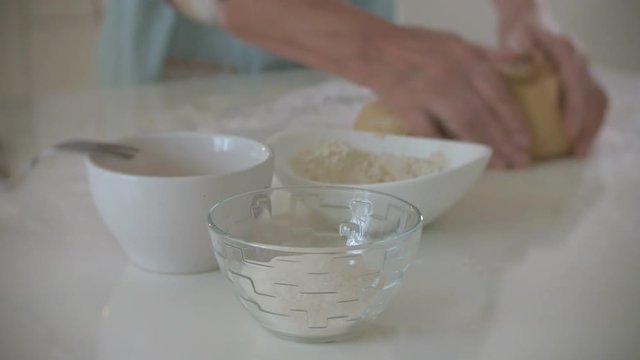 Happy senior woman rolling pizza dough at home in the kitchen