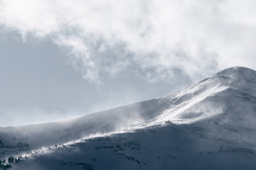 Strong wind gusts carry snow over Peak 8 near dusk in Breckenridge, CO
