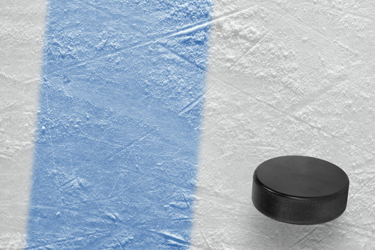 Puck and fragment of the ice arena with a blue line
