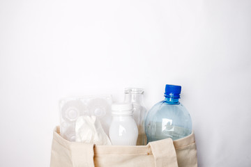 Composition with eco tissyue bag, paper, used box for eggs, packages, plastic, glass, prepared for recycling. Reduce, Reuse and Recycle concept. Flat lay, view from above, copy space