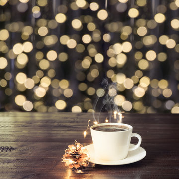 Cup of black coffee on wooden table in cafe. Blurred gold garland as background. Christmas Time. Image for display or montage your products.