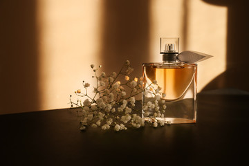 Transparent bottle of perfume with beautiful flowers on dark table - obrazy, fototapety, plakaty