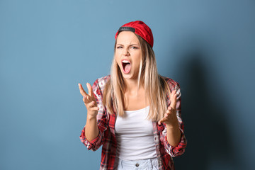 Angry young woman on color background