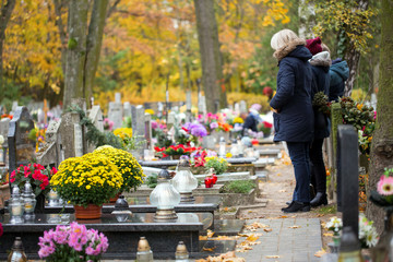 Family at the cemetery are praying at the grave - obrazy, fototapety, plakaty