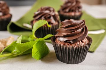 Tasty chocolate cupcake with mint on grey table, closeup