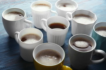 Many cups with tasty aromatic coffee on color wooden table